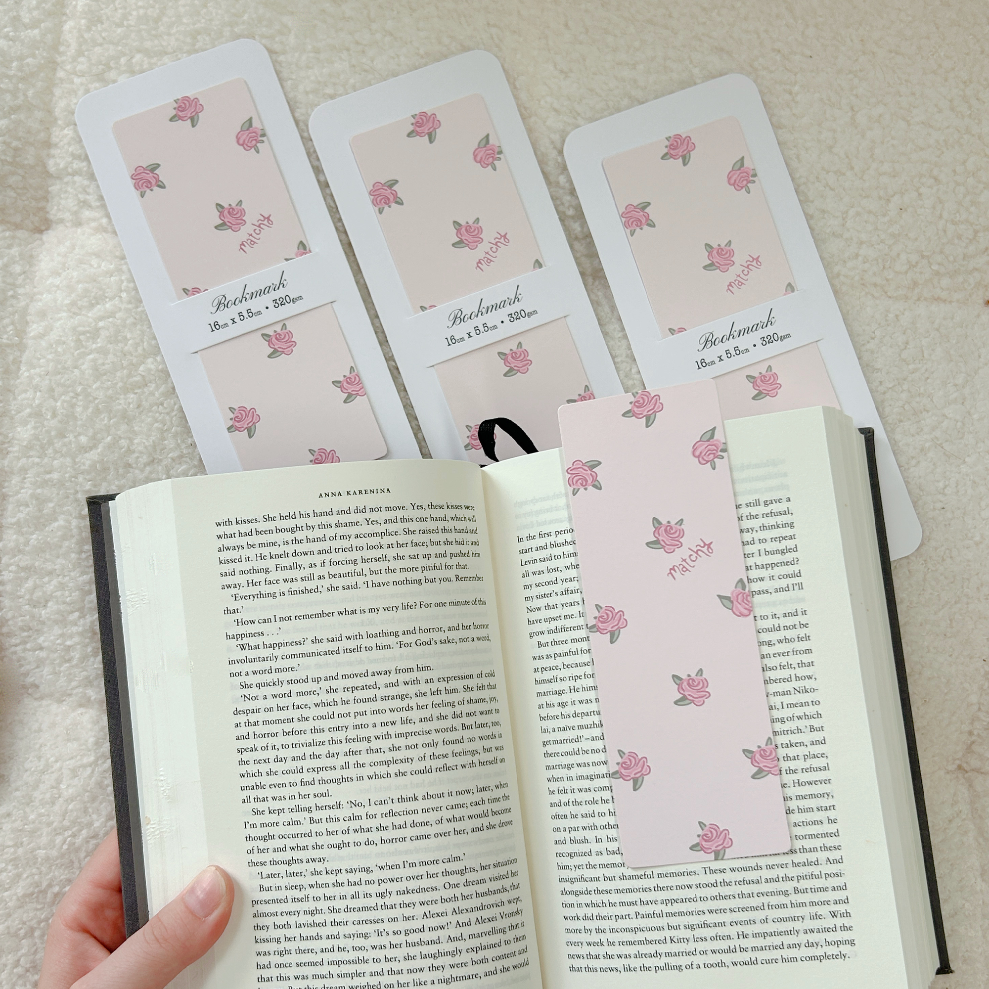 Soft pink bookmarks illustrated with small pink roses, with one tucked into an open book. Matchy Rose Bookmark.