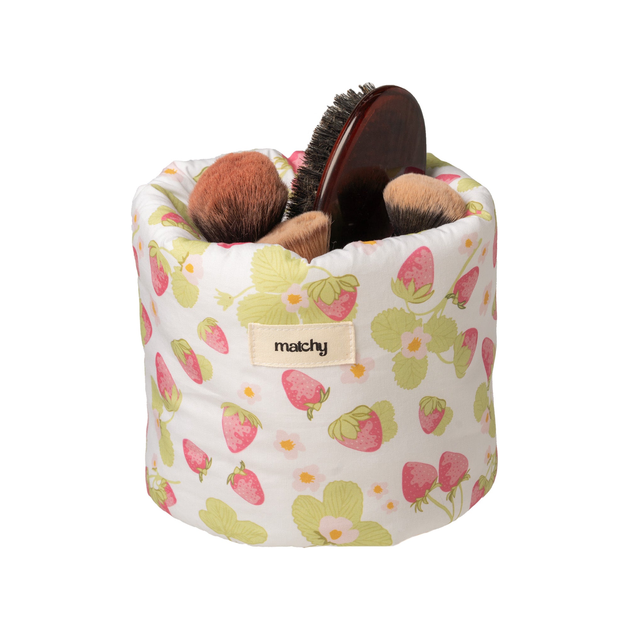 Strawberry print bubble bucket holding makeup brushes and a wooden hairbrush, with a 'matchy' label. Matchy Sofia Bubble Bucket, a padded vanity storage bucket.