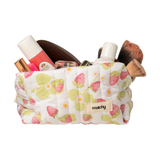 Strawberry print quilted carry-all bag overflowing with makeup brushes, lipsticks and skincare. Matchy Sofia Carry-All Bag, a quilted makeup and toiletry bag.