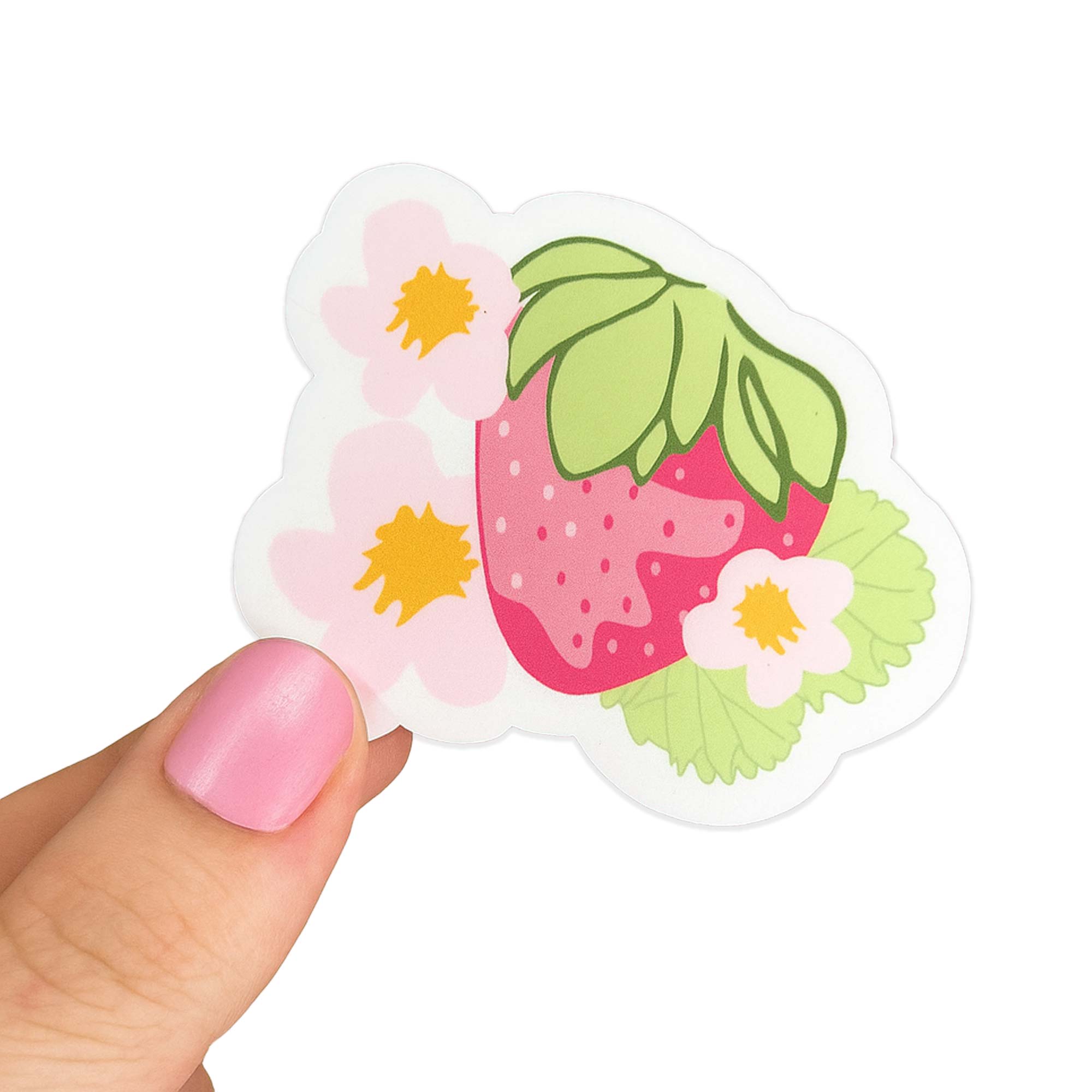 Hand with pink nails holding a die cut sticker of a pink strawberry with green leaves and pastel flowers. Matchy Sofia Sticker.